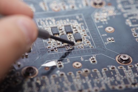 Human fingers making repair of motherboard. Close-up photo