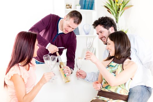 Group of happy friends sitting and drinking White Wine at Home Interior.