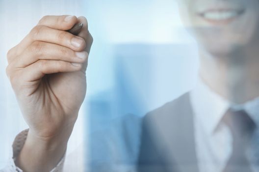 Young smiling businessman with pen behind the glass window