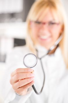 Young female doctor holding stethoscope / selective focus / focus on stethoscope.