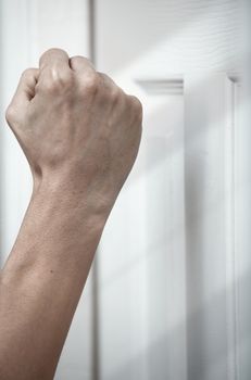 Human hand knocking at the wooden door