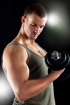 Young muscular man lifts a weight with biceps.