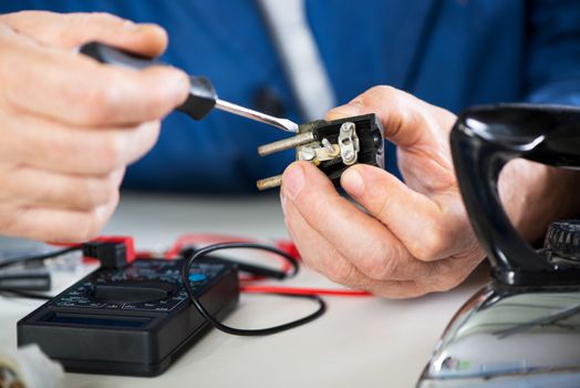 Electrician checking and repairing old power plug from iron. Close-up. Selective focus, Focus on power plug. 