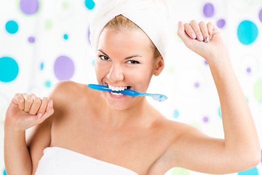 Young cute woman holding toothbrush with teeth. Looking at camera and smiling.