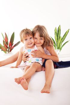 Two Happy little girls sitting hugging each other.