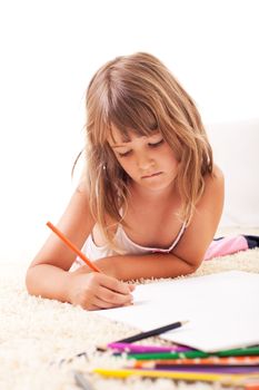 Cute little girl drawing with color crayons on the floor.