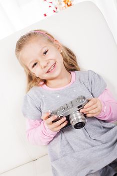 Cute little girl at home with a retro photo camera.