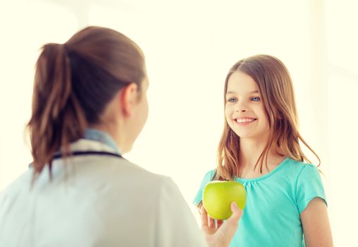 healthcare, child and medicine concept - female doctor giving an apple to smiling little girl