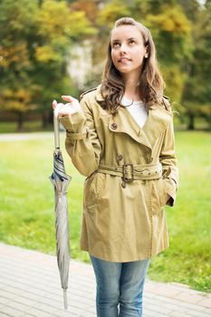 Young woman with umbrella standing in coat in the autumn park.