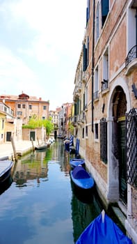 canal and boats with ancient buildings vetical in Venice, Italy