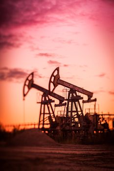 Oil pump jacks at sunset sky background. Selective focus, shallow depth of field