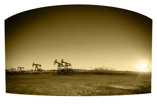 Oil pumps on the sunset sky background. Toned sepia.
