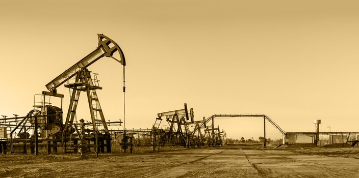 Pump jack group and wellheads. Extraction of oil. Toned.