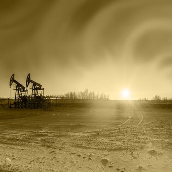 Oil pumps on the sunset sky background. Toned sepia.