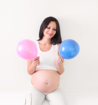 pregnant woman with blue and pink balloon