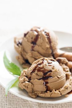 Chocolate ice cream with wafer on plate, table cloth background.