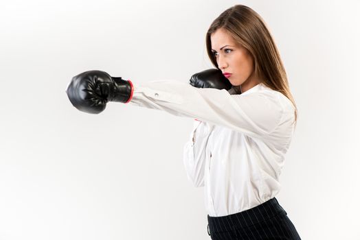 Serious businesswoman punching with boxing gloves. White background. 