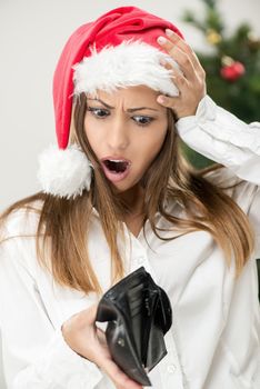 Young beautiful businesswoman wearing santa hat and looks worried at empty wallet.