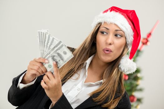 Successful businesswoman wearing santa hat and holding money. 