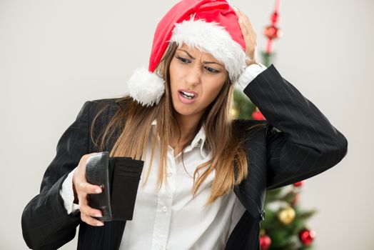 Young beautiful businesswoman wearing santa hat and looks worried at empty wallet.