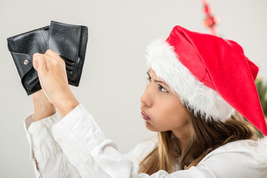 Young beautiful businesswoman wearing santa hat and looks worried at empty wallet.