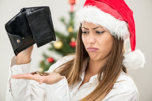 Young beautiful businesswoman wearing santa hat and looks worried at empty wallet.