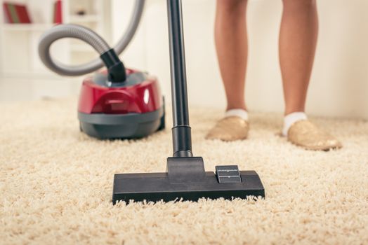 Woman vacuuming the house. Close-up with vacuum cleaner.