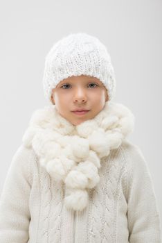 Portrait of a cute little girl in white winter clothes. Looking at camera.