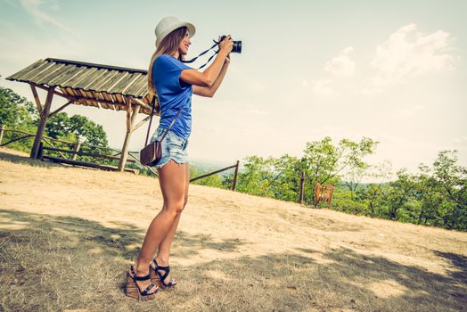 Young beautiful woman standing by viewpoint and taking photo for memory.