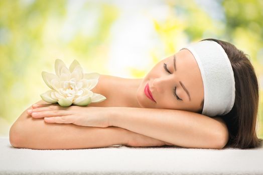 Cute young woman lying on a towel during a skincare treatment at a spa. She is relaxing  and enjoying with eyes closed. 