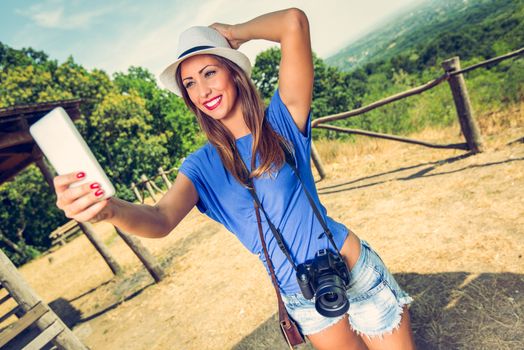 Young beautiful woman standing by viewpoint and taking selfie for memory from summer travel vacation.