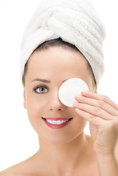Removing face makeup with cotton pad. Facial closeup of pretty  female model with perfect skin. Girl holding cotton swab on one her eye and looking at camera.