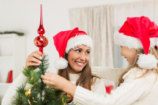 Young mother and her daughter decorating Christmas tree at home. 