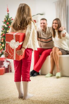 Cute little girl holding gift boxes for surprise her parents for Christmas or New Year. Selective focus.
