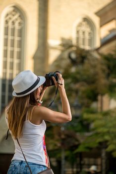 Beautiful young woman in the city photographing architecture with digital camera.