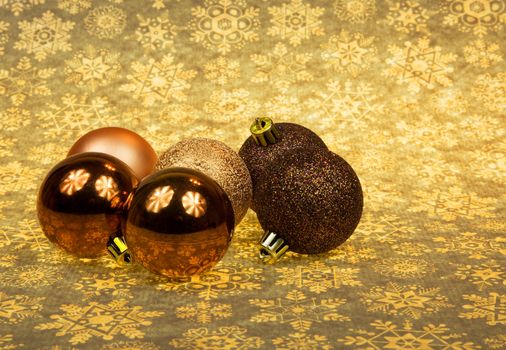 Five Christmas baubles ln a group on the Christmas brownish-yellow stars background.Horizontal view.