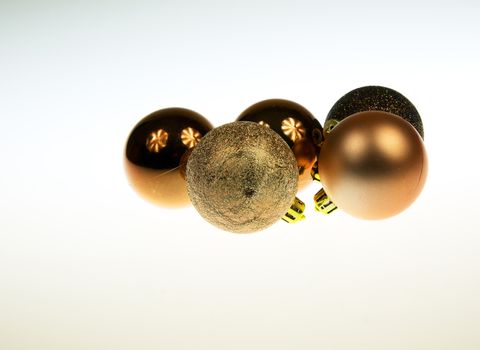Five golden and brown Christmas baubles together  with reflections on white isolated background.Horizontal view.