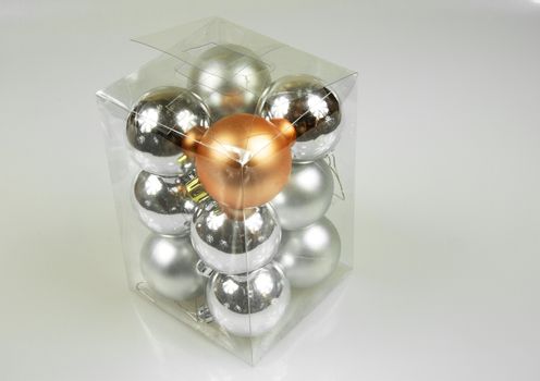 Transparent box with small Christmas trees baubles on a white background. Close view from above.