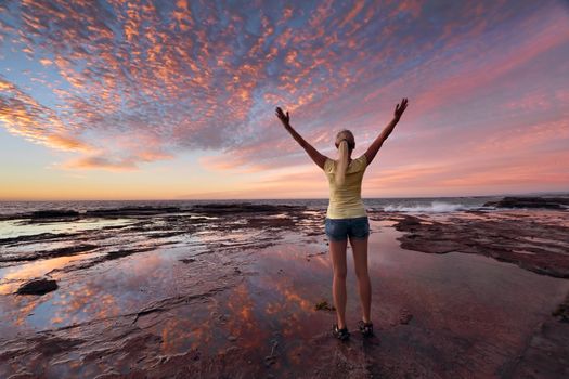 Woman with arms outstretched towards the sunrise sky celebrating life.  Jubilation, triumph, success, spiritual, exhilaration, 
