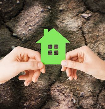 home, farming, energy saving, people and family concept - closeup of woman and man hands holding green house over ground background