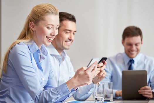 business, people, technology and teamwork concept - smiling businesspeople with smartphones and tablet pc computer meeting in office