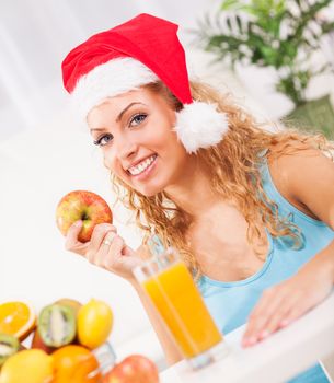 Beautiful young woman on New Year's day  eat apple in her home with Santa Hat
