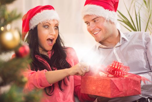 Beautiful happy Christmas couple with Glowing Christmas Present.
