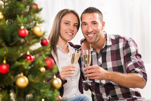 Young beautiful couple Celebrating Christmas or New Year with glass of champagne.