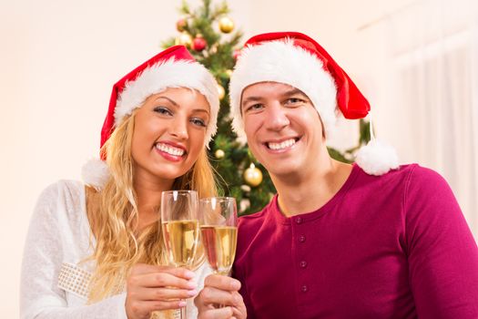 Young beautiful couple Celebrating Christmas or New Year with glass of champagne.