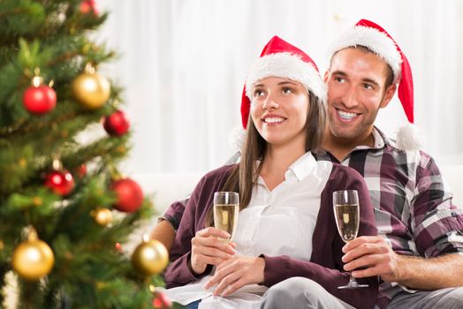 Young beautiful couple Celebrating Christmas or New Year with glass of champagne. 