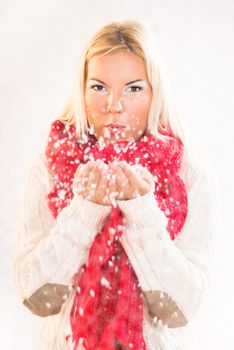 Beautiful happy winter girl blowing snow into the air.