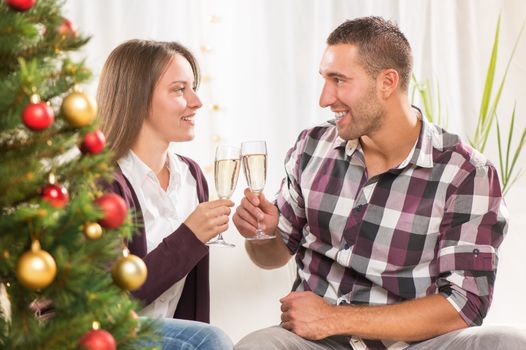 Young beautiful couple Celebrating Christmas or New Year with glass of champagne. 