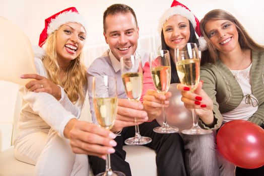 Happy friends Celebrating Christmas or New Year with glass of champagne in home interior.