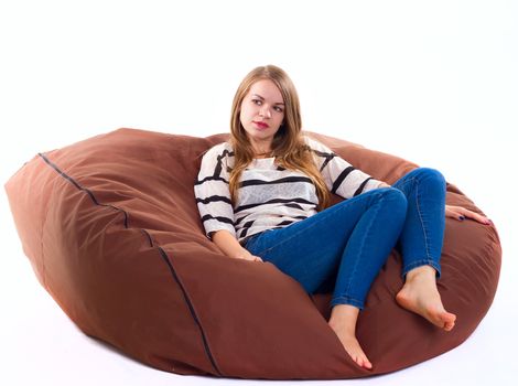 cute girl sitting on a braun beanbag chair.